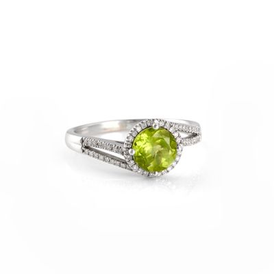 a close up of a ring with a green stone surrounded by diamonds
