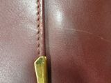 a close up of a brown leather bag with a gold handle