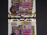 deux paquets de cartes à collectionner Pokémon posés sur une surface noire