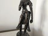 bronze statue of a woman holding a flower in her right hand