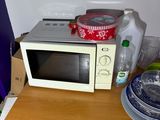a microwave sitting on top of a wooden table next to a refrigerator