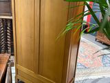 a tall wooden cabinet with a door on top of it