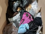 a cardboard box filled with clothes and bags of clothing