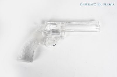 un gros plan d'un revolver posé sur une surface blanche, avec un fond blanc
