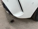 the front bumper of a white car with a hole in it