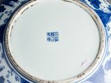 a blue and white plate with a picture of people on it