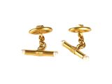 two pairs of gold cufflinks with a cigarette on a white background