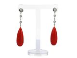 une paire de boucles d'oreilles rouges et blanches posées sur un présentoir blanc