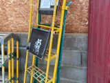 a yellow and green hand truck next to a red door