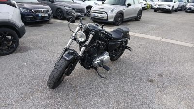 une moto garée sur un parking, à côté de nombreuses voitures