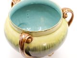 a blue and green bowl on a stand on a white surface