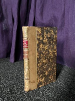 un vieux livre posé sur une table noire, à côté d'un rideau violet