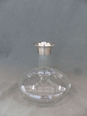 une bouteille en verre transparent avec un bouchon argenté posée sur une table