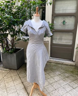 grey dress on a mannequin stand in front of a door