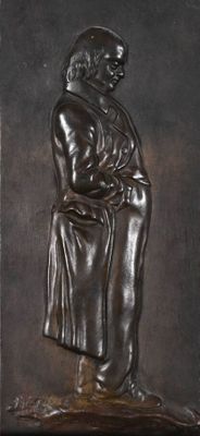 statue of a man in a robe holding a book on a pedestal
