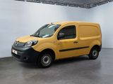 La camionnette jaune est garée dans une grande pièce aux murs blancs.