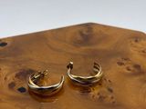 pair of gold plated hoop earrings sitting on top of a wooden board