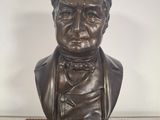 bronze bust of a man with a bow tie on a table