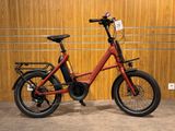 un vélo électrique rouge garé devant un mur en bois