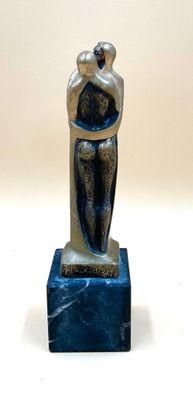 statue d'une femme tenant un enfant dans ses bras, posée sur un socle en marbre