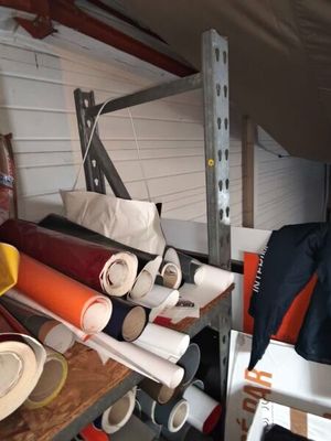 de nombreux rouleaux de tissu posés sur une étagère dans un garage