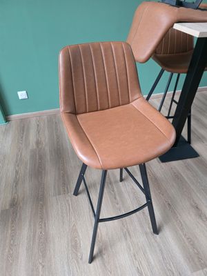 un tabouret de bar en cuir marron avec un piètement en métal noir