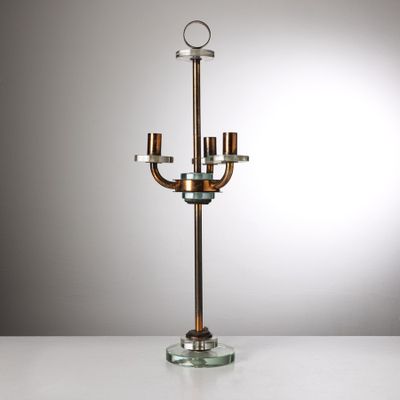 un chandelier en métal et en verre avec trois bougies, posé sur une table