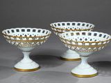 three white and gold decorated bowls on pedestals against a gray background