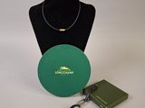 a green box with a necklace and a book on a table