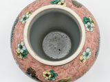 a pink vase with flowers on it on a white surface