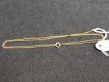 a gold necklace with a tag on it sitting on a table