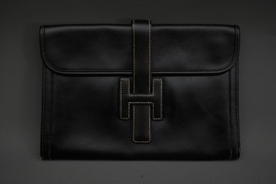 une pochette en cuir noir ornée d'une croix sur le devant
