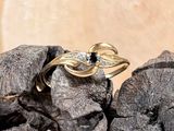 une bague en or sertie d'une pierre noire, posée sur un tas de pierres