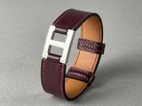 un gros plan d'un bracelet en cuir marron posé sur une surface grise