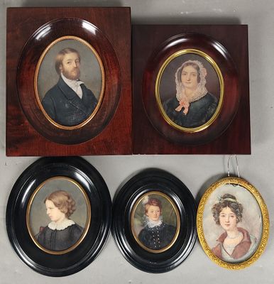 trois portraits encadrés représentant un homme et une femme, accrochés au mur