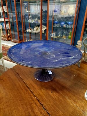 un plat à gâteau en verre bleu posé sur une table en bois