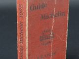 an old red book sitting on top of a table next to a black background