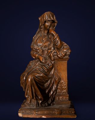 une statue en bronze représentant une femme assise sur une table