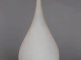 a white vase with a wooden handle sitting on top of a table