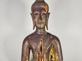une vieille statue en bois représentant un Bouddha assis sur une surface blanche