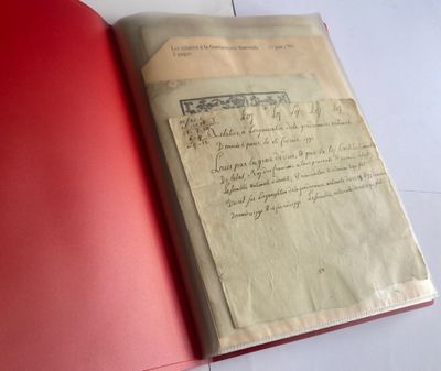 an open book with a red cover sitting on top of a table