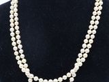 a white pearl necklace on a black mannequin