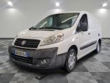 La petite camionnette blanche est garée dans une grande pièce au sol carrelé en damier.