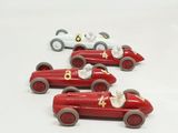 four toy cars that are sitting on a white surface