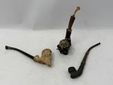 two pipes and a pipe holder on a white surface