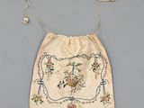 a white bag with a floral design and pearls hanging from it