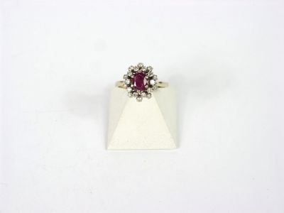 un gros plan d'une bague ornée d'une pierre rouge sur un fond blanc