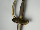 une vieille épée avec une poignée en or sur une surface blanche