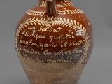un vase marron et blanc, orné d'une inscription, posé sur une surface grise