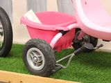a pink tricycle sitting on the grass in front of a building